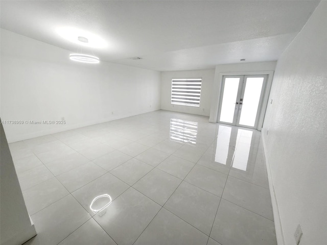 empty room with light tile patterned floors and french doors