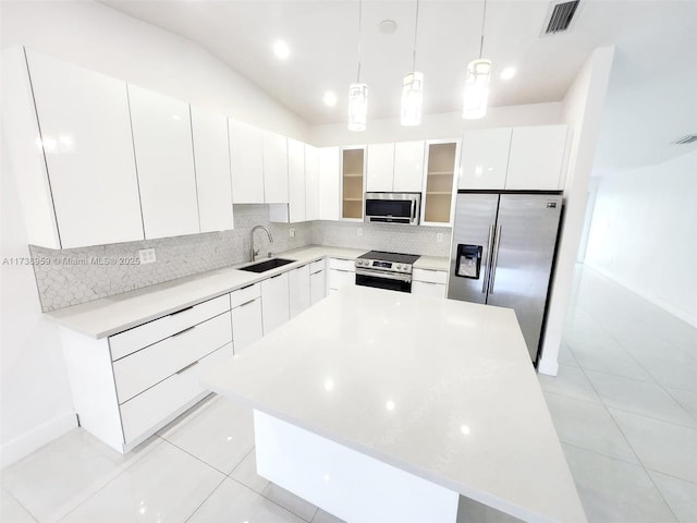 kitchen with stainless steel appliances, sink, a kitchen island, and white cabinets