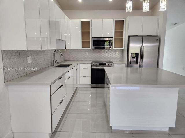 kitchen featuring sink, appliances with stainless steel finishes, white cabinetry, hanging light fixtures, and a kitchen island