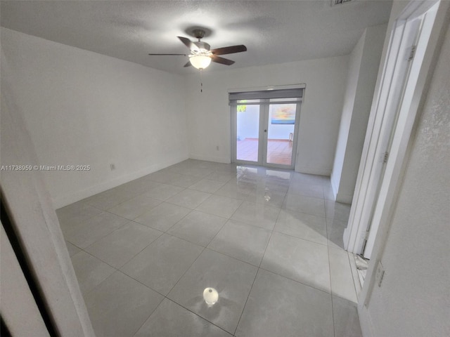 tiled empty room featuring ceiling fan and a textured ceiling