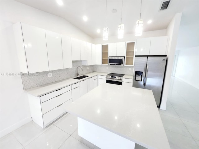 kitchen with sink, white cabinetry, stainless steel appliances, a kitchen island, and decorative light fixtures