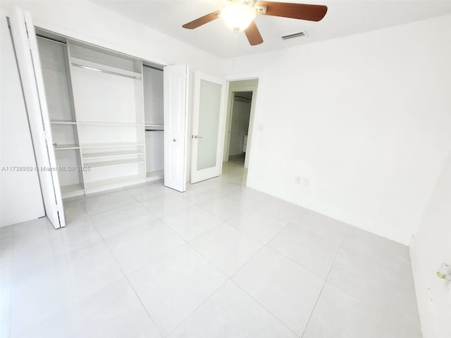 unfurnished bedroom with light tile patterned flooring, ceiling fan, and a closet