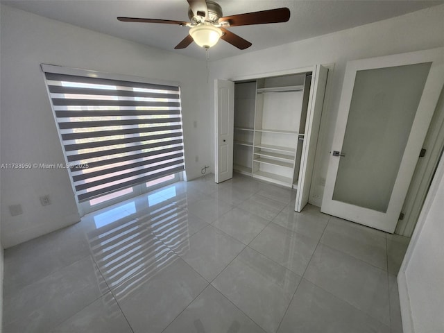 unfurnished bedroom with light tile patterned flooring, ceiling fan, and a closet