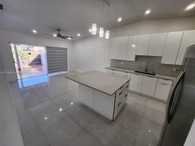 kitchen with white cabinetry, sink, a kitchen island, and stainless steel refrigerator