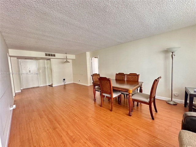 dining space with light hardwood / wood-style floors and a textured ceiling