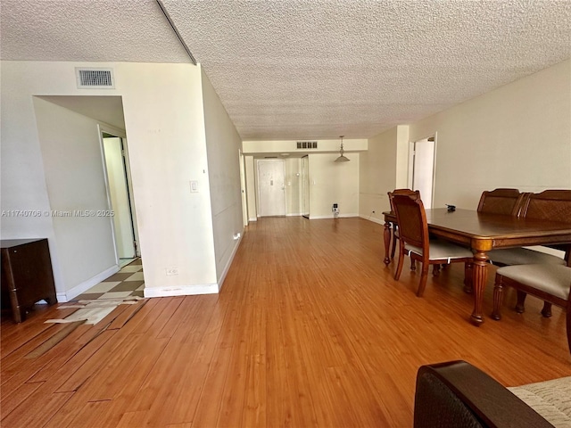 dining space featuring wood-type flooring and a textured ceiling