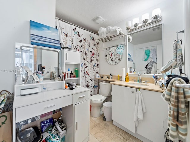 bathroom featuring vanity, a textured ceiling, and toilet