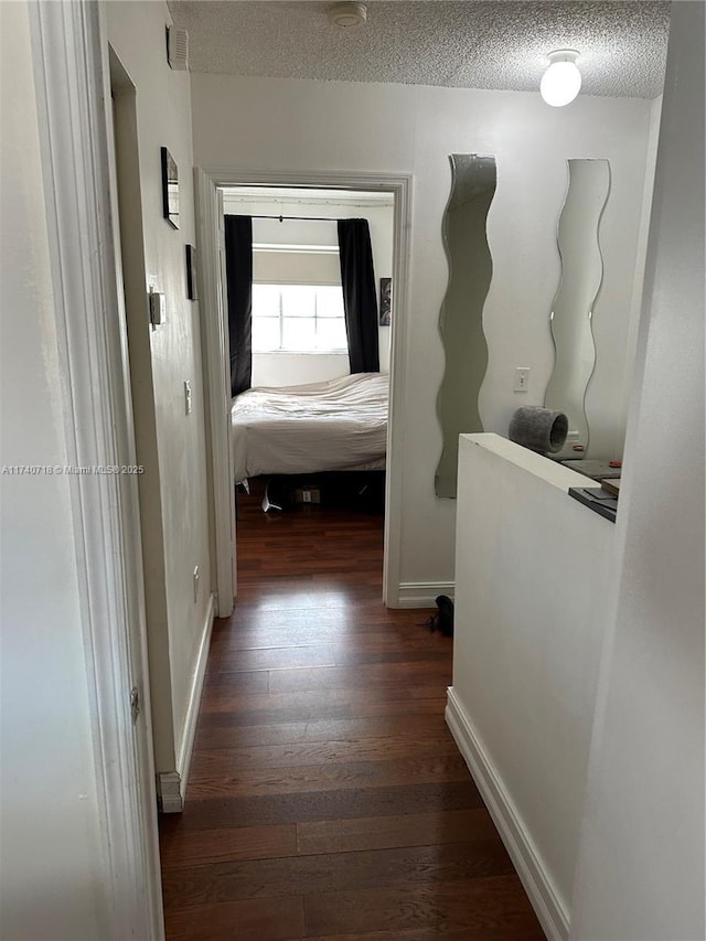 hallway with dark hardwood / wood-style floors and a textured ceiling