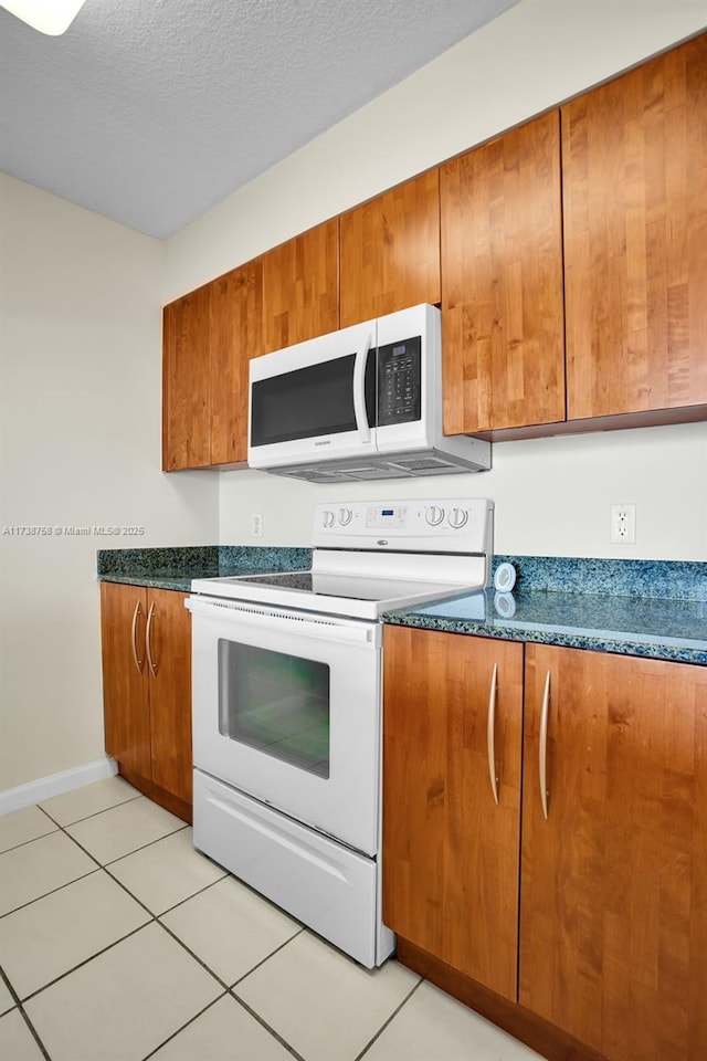 kitchen featuring light tile patterned floors, a textured ceiling, and white appliances