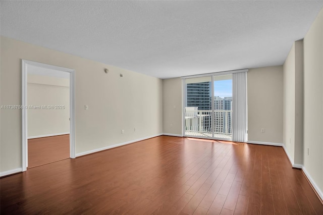 spare room featuring hardwood / wood-style floors, a wall of windows, and a textured ceiling