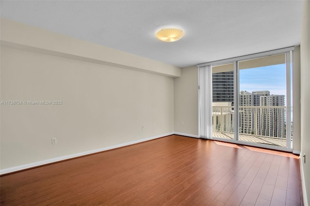 unfurnished room with wood-type flooring, floor to ceiling windows, and a textured ceiling