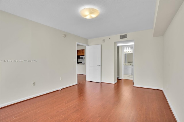 unfurnished bedroom with wood-type flooring and ensuite bathroom