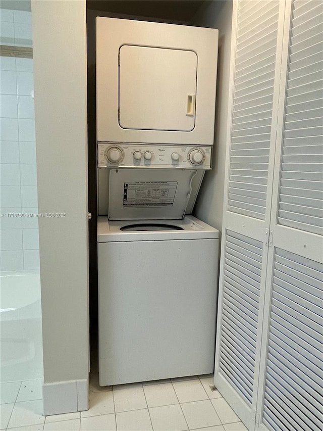 laundry room featuring stacked washer / drying machine and light tile patterned floors