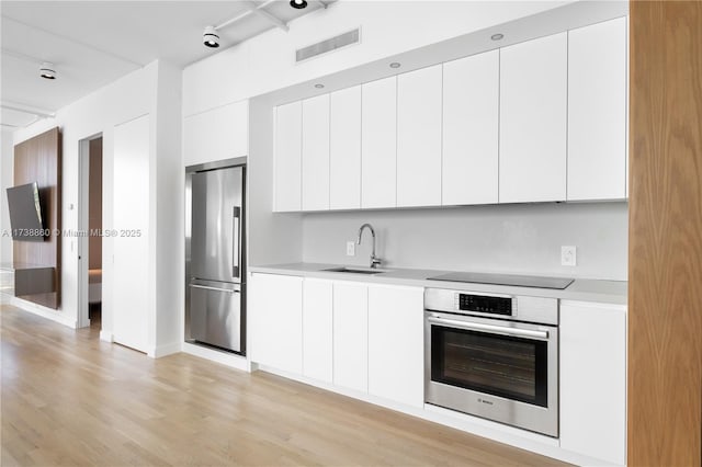 kitchen with appliances with stainless steel finishes, sink, and white cabinets