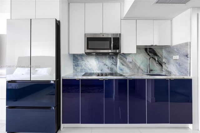 kitchen with sink, fridge, white cabinets, black electric stovetop, and backsplash