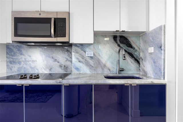 kitchen featuring white cabinetry, black electric stovetop, sink, and tasteful backsplash