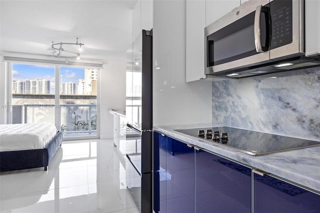 kitchen with light tile patterned floors, white cabinets, black electric cooktop, and decorative backsplash