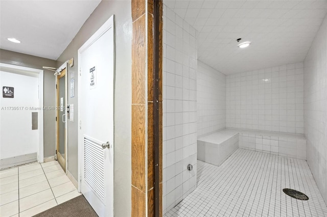 bathroom with tile patterned flooring and a tile shower