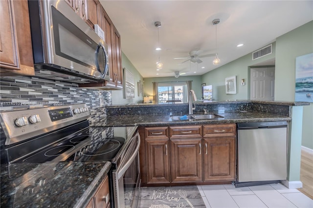 kitchen with decorative light fixtures, sink, decorative backsplash, dark stone counters, and stainless steel appliances