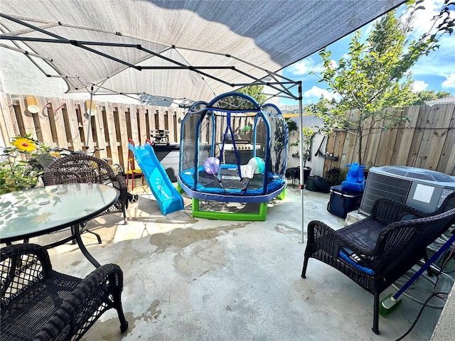 view of patio / terrace with cooling unit, a trampoline, and a playground