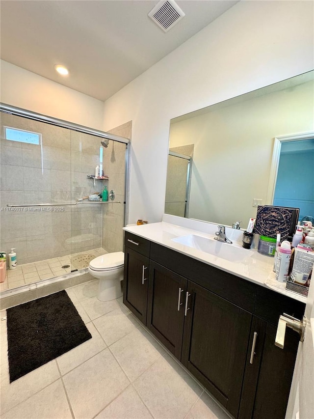 bathroom with tile patterned floors, toilet, a shower with shower door, and vanity