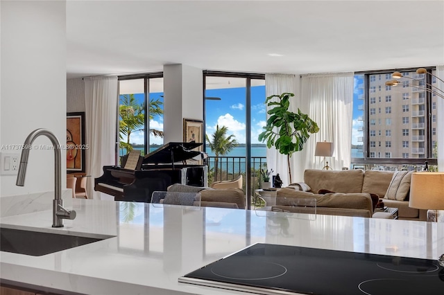 kitchen featuring black electric cooktop, sink, a wall of windows, and a water view