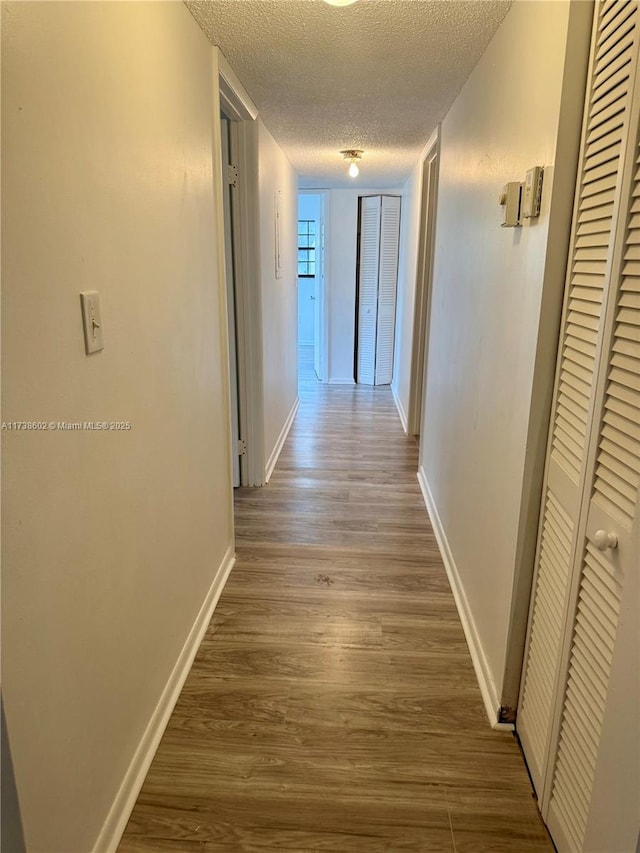 corridor featuring dark wood-type flooring and a textured ceiling