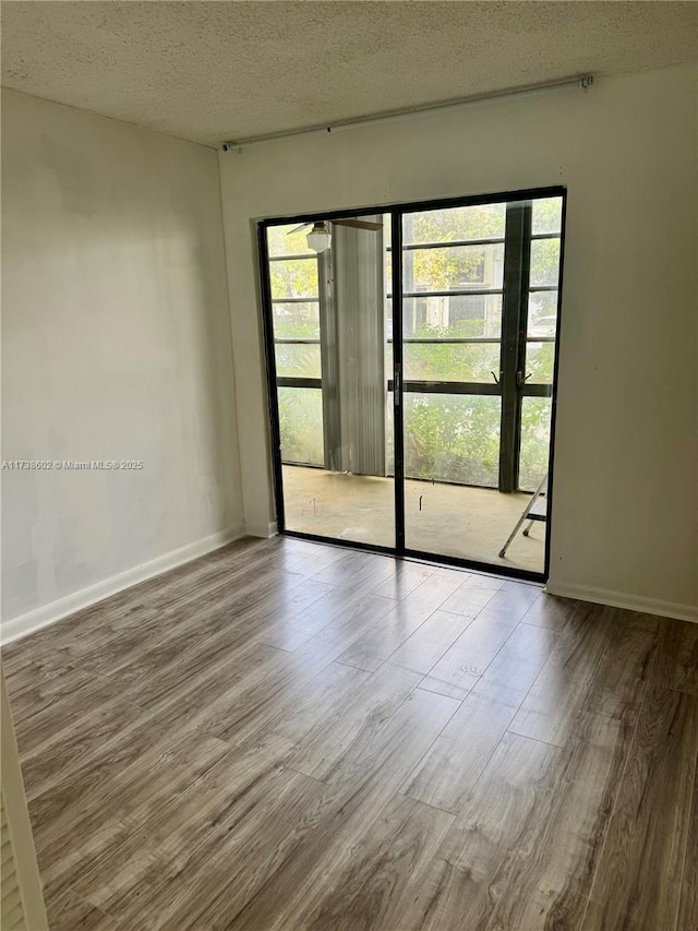 unfurnished room featuring hardwood / wood-style flooring and a textured ceiling