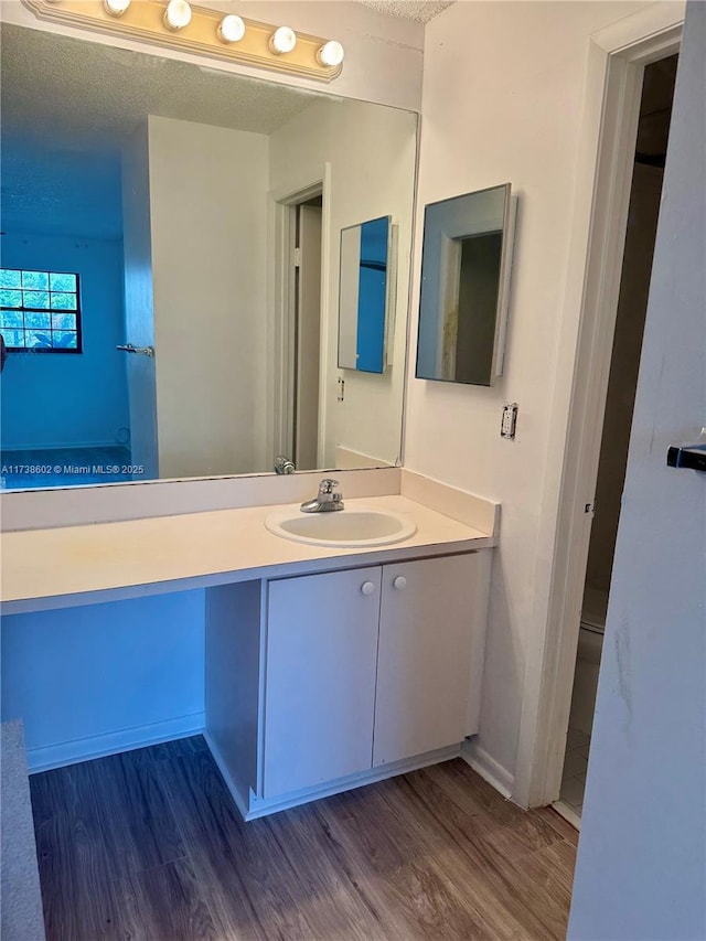 bathroom featuring wood-type flooring, vanity, and a textured ceiling