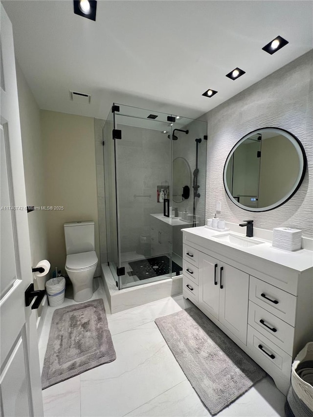 bathroom with walk in shower, vanity, and toilet