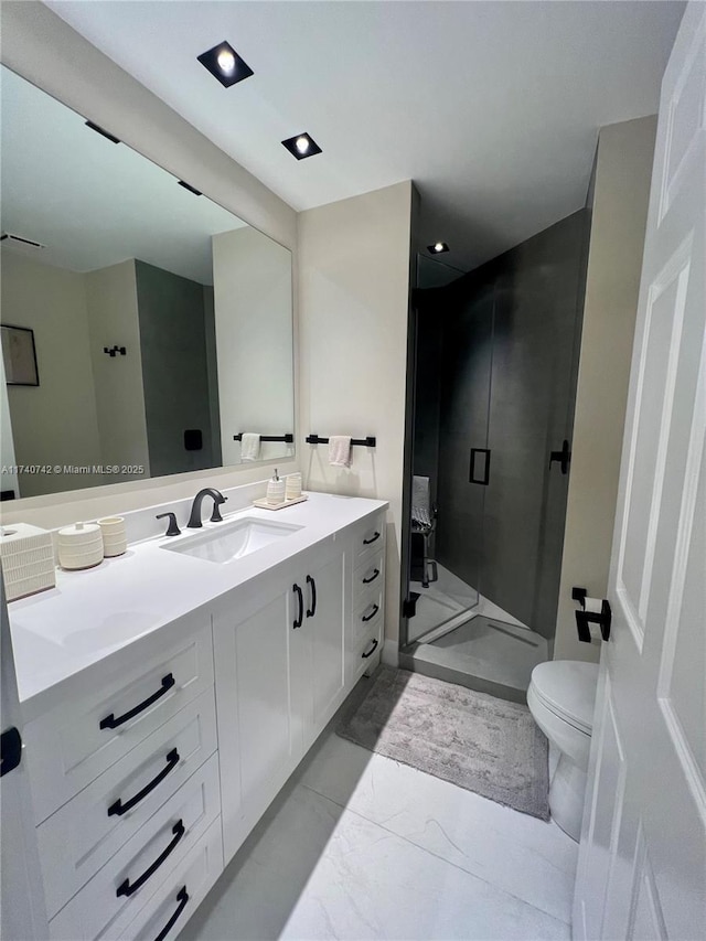 bathroom with vanity, a shower with door, and toilet