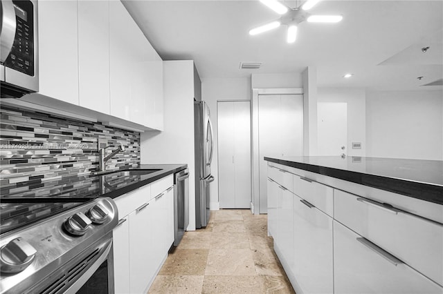 kitchen featuring stainless steel appliances, white cabinetry, sink, and backsplash