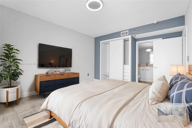 bedroom with ensuite bath, a closet, and light wood-type flooring