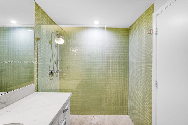 bathroom with tiled shower and vanity