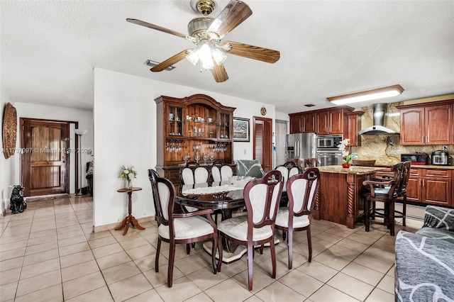 dining space featuring ceiling fan, light tile patterned floors, and a textured ceiling