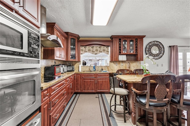 kitchen featuring a breakfast bar, sink, light stone counters, tasteful backsplash, and stainless steel appliances