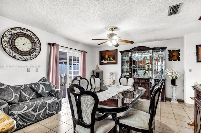 tiled dining room with a textured ceiling and ceiling fan