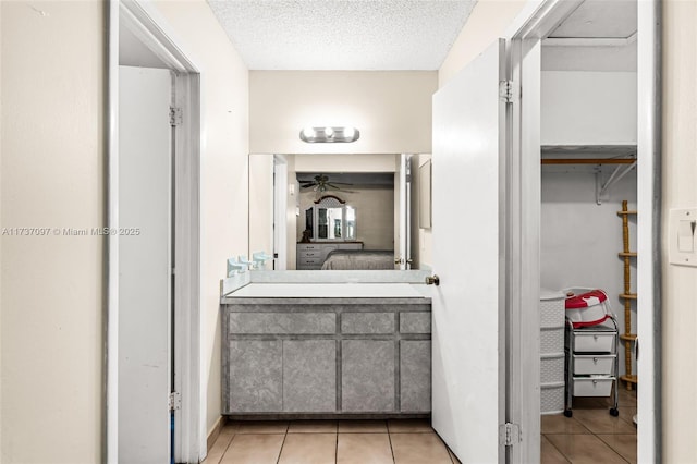 bathroom featuring ceiling fan, vanity, tile patterned flooring, and a textured ceiling