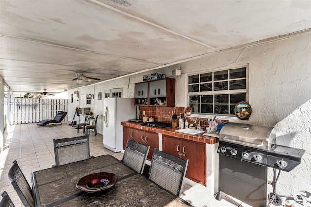 view of patio with sink, an outdoor kitchen, ceiling fan, and a grill