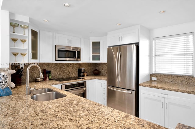 kitchen featuring white cabinetry, sink, backsplash, stainless steel appliances, and light stone countertops