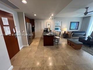 kitchen featuring a kitchen island, a breakfast bar area, stainless steel fridge, and ceiling fan