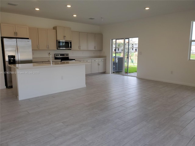 kitchen featuring appliances with stainless steel finishes, sink, a center island with sink, and light wood-type flooring