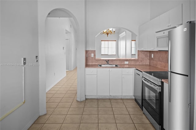 kitchen featuring white cabinetry, sink, light tile patterned floors, and stainless steel appliances
