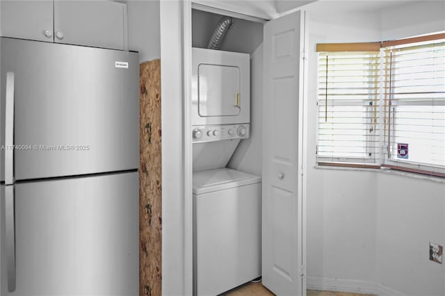 clothes washing area with stacked washer and clothes dryer and a wealth of natural light