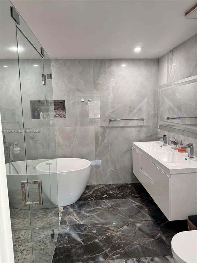 full bathroom with vanity, tile walls, shower with separate bathtub, and toilet