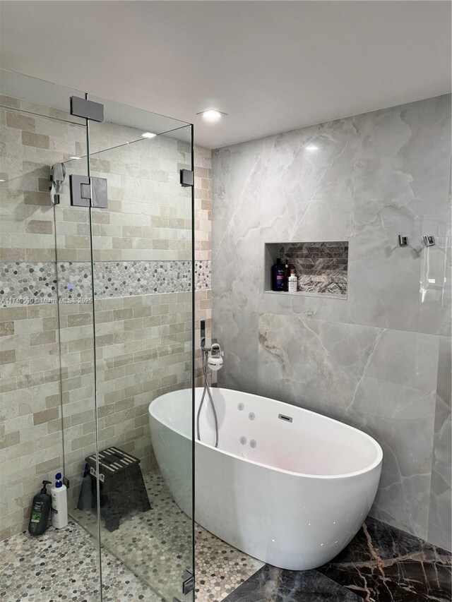 bathroom with tile walls and separate shower and tub