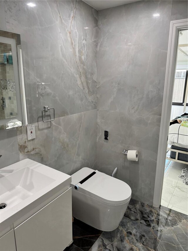 bathroom with vanity, tile walls, and toilet