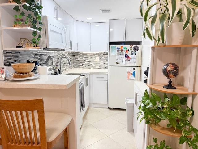 kitchen with light tile patterned flooring, a breakfast bar, sink, white cabinetry, and white appliances