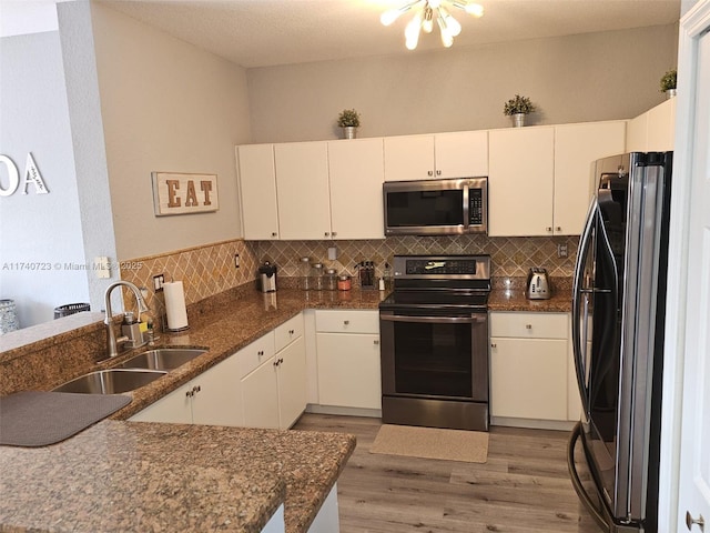 kitchen featuring sink, hardwood / wood-style floors, stainless steel appliances, white cabinets, and kitchen peninsula