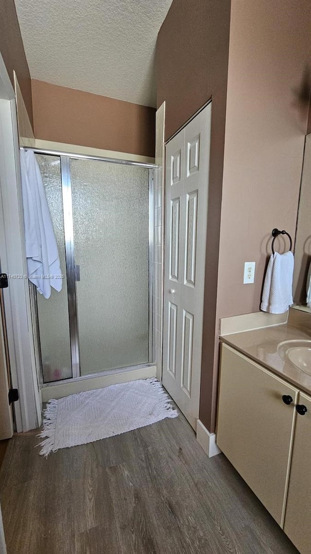 bathroom featuring vanity, hardwood / wood-style floors, a textured ceiling, and walk in shower